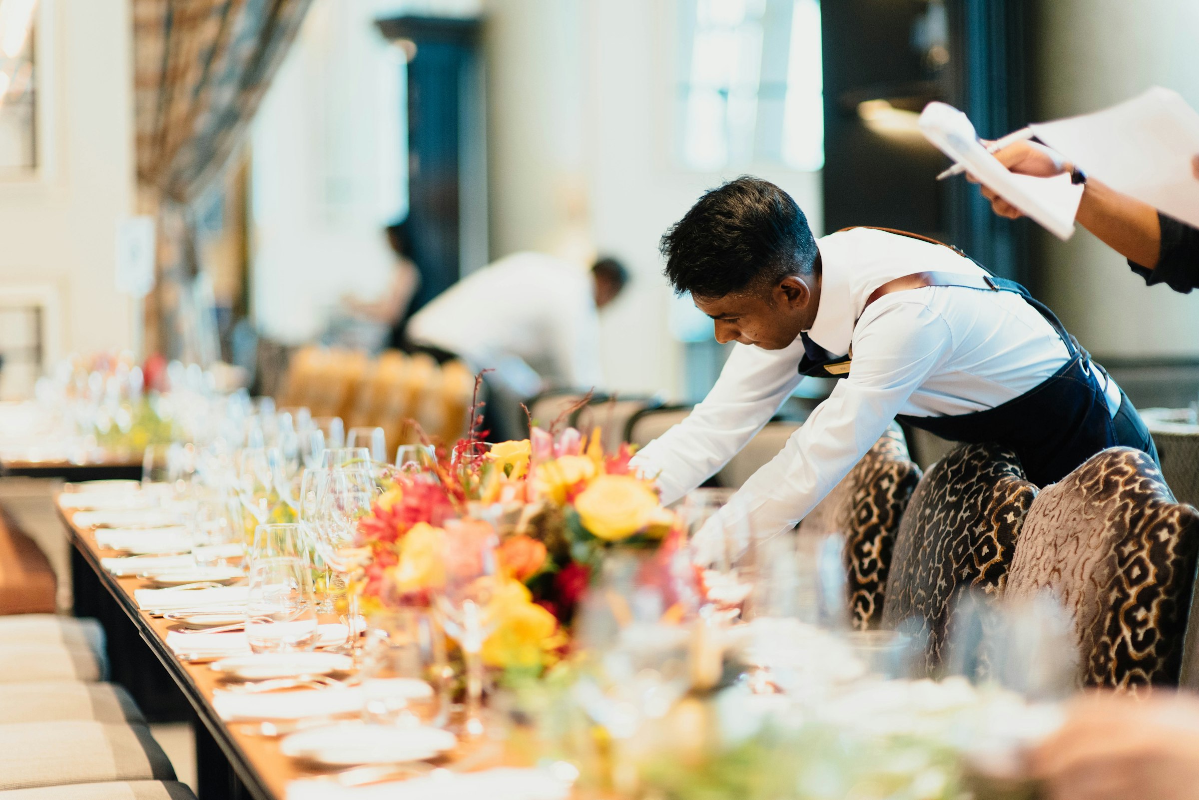 Un serveur dresse une longue table avant le service